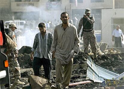 Dos hombres caminan entre los escombros de la comisaría de policía objeto de un atentado con camión bomba perpetrado ayer en Bagdad.