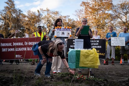 Una asistente coloca flores frente a un altar durante una vigilia frente a la entrada de Alligator Alcatraz