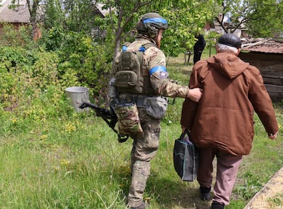 A Ukrainian police officer helps an elderly man be evacuated in Vovchansk on May 16.