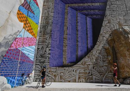 Los ciclistas se fotografían delante de las pinturas en las paredes de una cantera de piedra caliza durante el festival "Street art on the Roc", en Villars-Fontaine cerca de Dijon (Francia).
