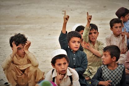 Varios niños responden a la petición del profesor de participar durante una clase al aire libre en un pueblo sin colegio de la provincia afgana de Kandahar.