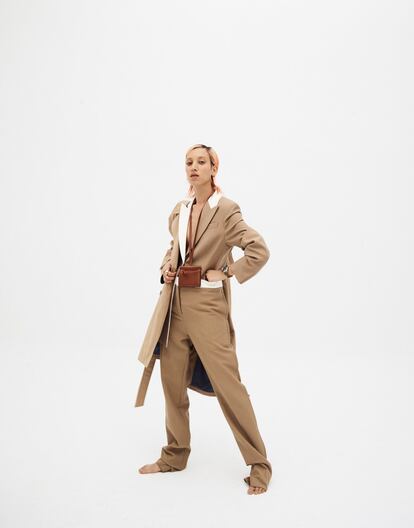 Traje con detalles en raso blanco de Loewe, gabardina clásica color camel de Herno, minibolso llavero de Gabriela Hearst para Mytheresa.com, sortija de oro de Isidoro Hernandez y reloj Panerai Luminor Due 3 Days.
