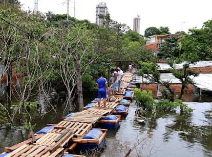 Un grupo de personas pasando sobre un puente flotante armado por los lugareños de un barrio de Asunción (Paraguay).