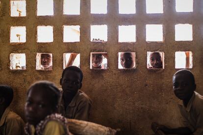 Niños asisten a clase mientras sus compañeros observan a través de los ventanucos en la aldea de Bodouakro, en el departamento de Daloa, en Costa de Marfil.