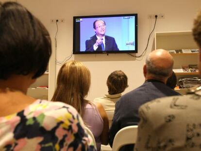 Un grupo de miembros del PS franc&eacute;s sigue el debate de primarias en Marsella. En la pantalla, el candidato Fran&ccedil;ois Hollande.