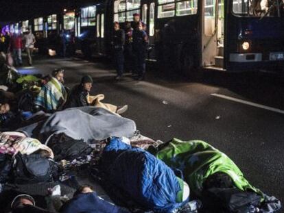 Policies vigilen refugiats que descansen a l'autopista en el seu camí cap a Budapest (Hongria), el 7 de setembre del 2015.