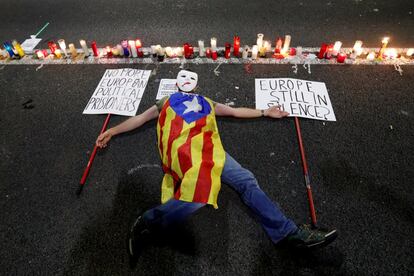 Un hombre tumbado en el suelo junto a velas durante la concentración en el centro de Barcelona.