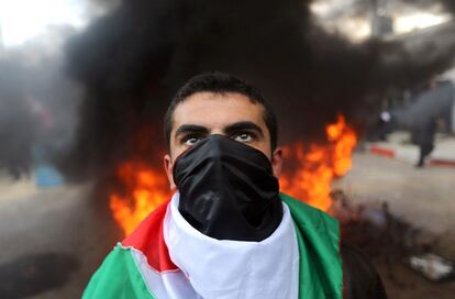 Un manifestante, se cubre la cara con una bandera palestina, durante una protesta contra la sede de las Naciones Unidas en la ciudad de Gaza, después de que la ONU anunciara la falta de fondos para reconstruir el territorio palestino.