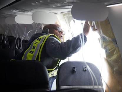 Un inspector de la Junta Nacional de Seguridad en el Transporte examina el hueco en el fuselaje del avión de Alaska Airlines que tuvo que hacer un aterrizaje de emergencia en Portland (Oregón) el viernes.