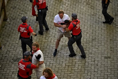 Un policía foral no deja avanzar a la gente que intenta acceder a la plaza de toros al término del encierro.