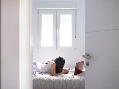 Una adolescente con el portátil y el móvil en su habitación.