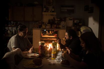 La familia de Rocío Fernández cena hamburguesas en el salón con la única luz del fuego.