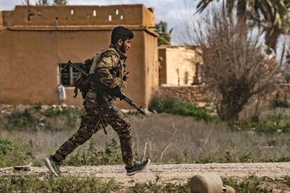 Un miembro de las Fuerzas Democráticas Sírias corre para ponerse a cubierto durante los bombardeos al último asentamiento del Estado Islámico en Baghouz, en la provincia siria de Deir Ezzor.