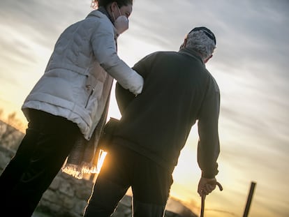 Una cuidadora pasea con un hombre mayor en Madrid.