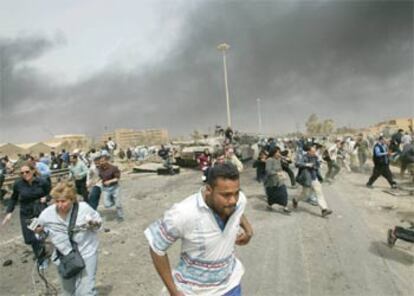 Unos reporteros corren en una calle de Bagdad, el 6 de abril, ante la llegada de aviones.