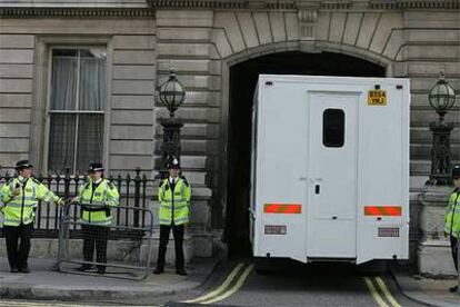 Tres policías vigilan la entrada de un furgón policial en los juzgados de Bow Street, en Londres.