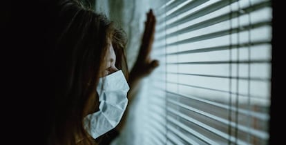 Una mujer mira por una ventana. Getty