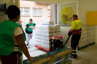 Voluntaris de l'organització El Gra de Blat, a Sants, descarreguen aliments.