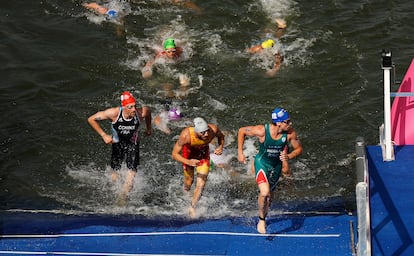 El deportista español González García (en el centro) sale de la prueba de nado en el río Sena. 