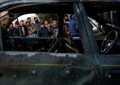 Un grupo de gente mira un vehículo por el atentado suicida con bomba en Kabul (Afganistán).
