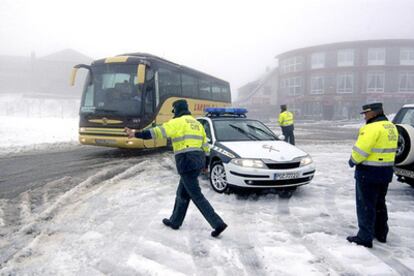 Agentes de la Guardia Civil regulan el tráfico en plena nevada en el alto de Navacerrada.