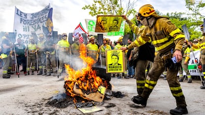 Un bombero quema una imagen del presidente de la Junta de Castilla y León en una protesta frente al edificio de las Cortes.