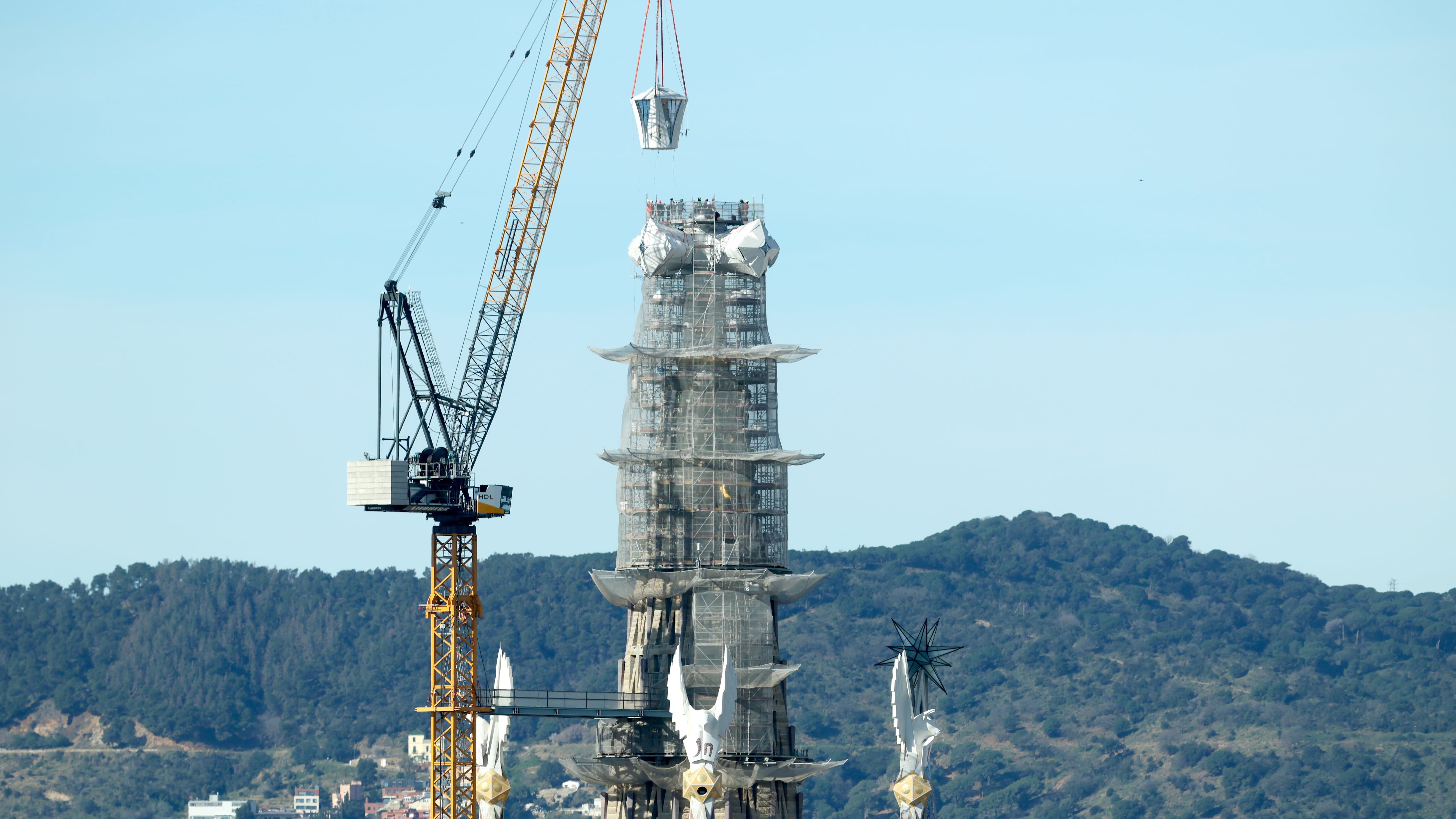 Operarios de la Sagrada Familia colocan el brazo superior de la cruz de la Torre de Jesús.