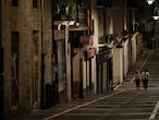 Residents wearing face mask protection as they walk along an empty Javier street, in Pamplona, northern Spain, Saturday, Oct. 24, 2020, as new measures against the coronavirus began in the Navarra province where all bar and restaurants are closed for 15 days from Wednesday midnight. (AP Photo/Alvaro Barrientos)