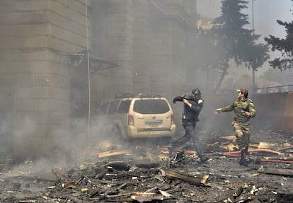 Dos policas corren escapando de los escombros que caen de un edificio de pisos incendiado en Bak (Azerbaiyn). Al menos quince personas murieron y 30 tuvieron que ser hospitalizadas a consecuencia de un incendio en un edificio de 16 plantas situado en el barrio de Binagadi, en el norte de la capital azerbaiyana, que los bomberos han tardado varias horas en sofocar.