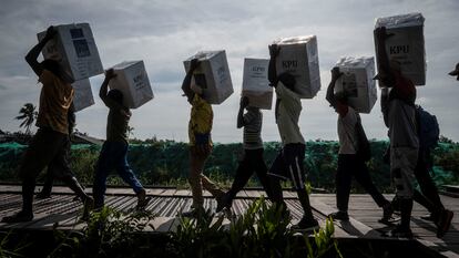 Unos voluntarios llevan urnas de cartón a los colegios electorales en Asmat, al sur de la provincia indonesia de Papúa, el 13 de febrero.