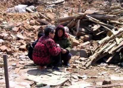 Dos mujeres norcoreanas, entre los restos de la tragedia.