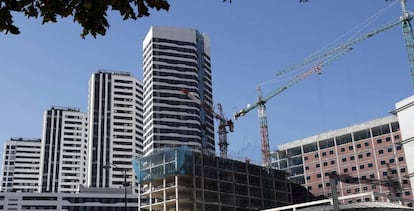 Un edificio en construcción junto a viviendas. 