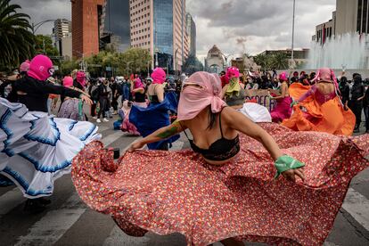 Mujeres del colectivo 'Capuchas Rosas' acompañan la marcha con música y baile, retratadas frente a la fuente del Caballito.