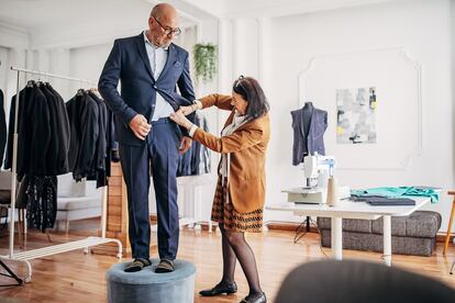 Una sastra toma medidas de un traje a un cliente.