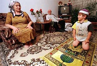 El niño checheno Imam, de tres años, aprende a rezar junto a su abuelo y su tía en un piso de Moscú.