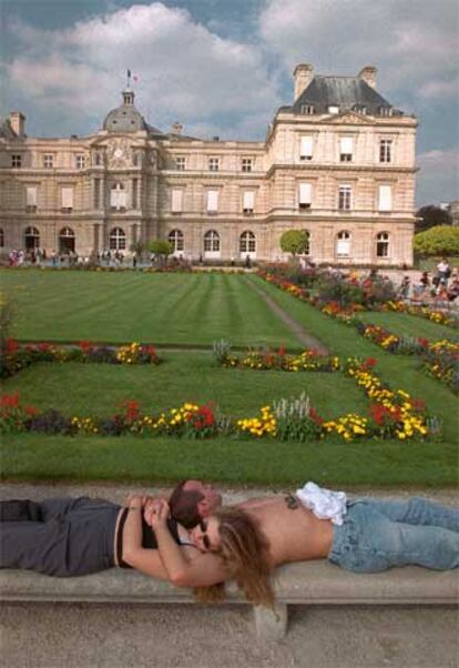 Una pareja descansa en el jardín de Luxemburgo (al fondo, el Senado).