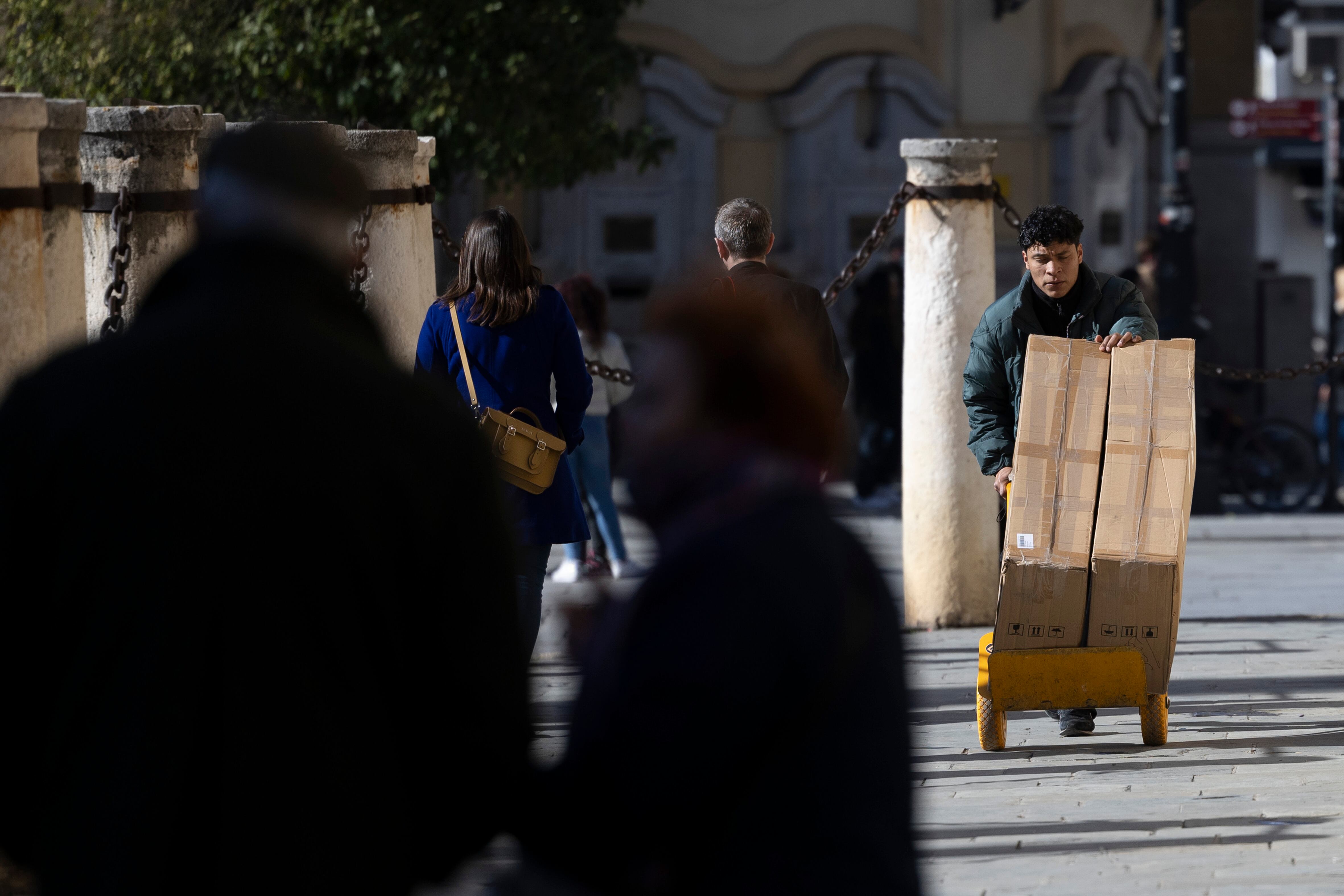 Un joven traslada mercancía con una carretilla en Sevilla (Andalucía), en febrero de 2024.