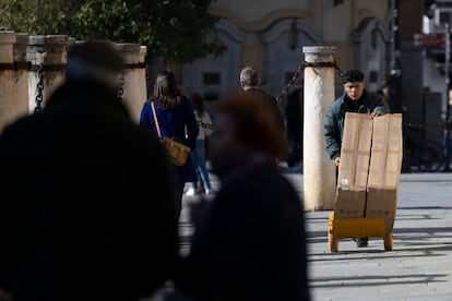 Un joven traslada mercancía con una carretilla, en Sevilla.