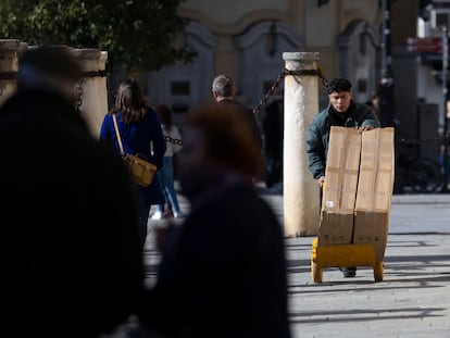 Un joven traslada mercancía con una carretilla en Sevilla.