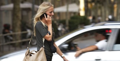 Una mujer joven camina hablando por su tel&eacute;fono m&oacute;vil por Barcelona