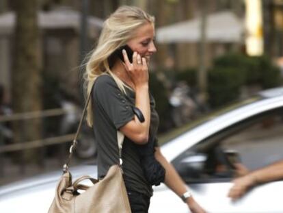 Una mujer joven camina hablando por su teléfono móvil por Barcelona