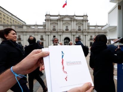 AME4277. SANTIAGO (CHILE), 14/12/2023.- Un hombre sostiene un libro de la Propuesta Constitucional de Chile luego de recibirlo en un punto de entrega del borrados para conocimiento de la ciudadanía,  el 17 de noviembre de 2023, en Santiago (Chile). El rumbo que tomó el segundo proceso constituyente atrapó al progresismo chileno en una gran paradoja: tener que defender la Constitución vigente, que repudió durante décadas por su origen dictatorial, ante la posibilidad de aprobarse una propuesta de carta magna con sello conservador y considerada más regresiva que la heredada del régimen. El contrasentido es tal que la extrema derecha, que nunca apostó por cambiar el texto fundamental vigente, junto a la derecha tradicional, defienden en el plebiscito de este domingo sustituir el redactado actual; mientras que quienes siempre habían insistido en una nueva propuesta ahora apuestan por mantenerlo. EFE/ Elvis González
