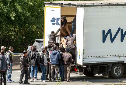 Un grupo de inmigrantes ilegales se introducen en el remolque de un camión que se encuentra parado en la A16 en la entrada de acceso al Eurotúnel cerca de Calais (Francia).