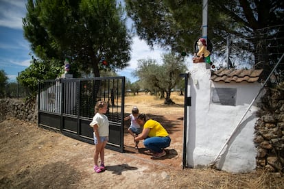 Montaña Ferrer y ata los cordines a una de sus hijas en el acceso a su casa en Aldea del Cano (Extremadura).