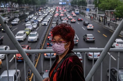 Mulher protegida por máscara cruza por uma passarela em Wuhan, em 14 de maio.