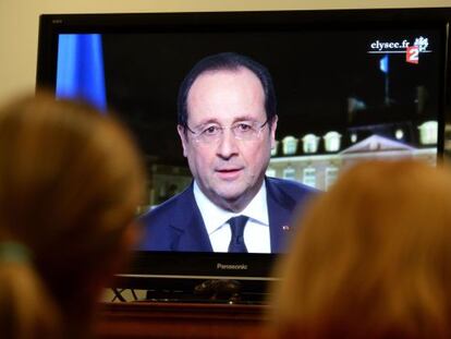 Dos personas siguen el discurso de Hollande.