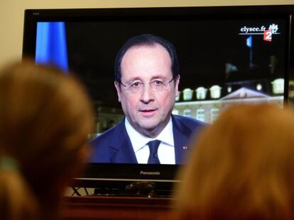 Dos personas siguen el discurso de Hollande.