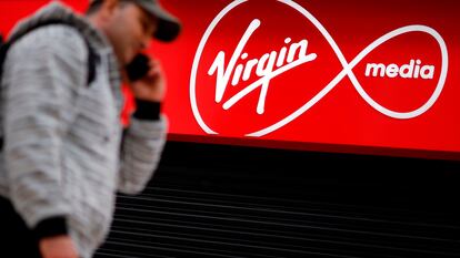 A person walks past a Virgin Media mobile phone store, closed-down due to the COVID-19 pandemic, in London on May 4, 2020. - Spanish group Telefonica on Monday said it was in talks with US cable giant Liberty Global to merge their telecoms operations in the UK.  In a statement, Madrid-based Telefonica said it was in "talks... about a possible integration" of its O2 mobile business and Liberty's Virgin Media that provides a mix of telecoms and television services, while providing caution over a deal ending up being struck. (Photo by Tolga Akmen / AFP)