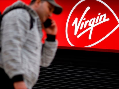 A person walks past a Virgin Media mobile phone store, closed-down due to the COVID-19 pandemic, in London on May 4, 2020. - Spanish group Telefonica on Monday said it was in talks with US cable giant Liberty Global to merge their telecoms operations in the UK.  In a statement, Madrid-based Telefonica said it was in "talks... about a possible integration" of its O2 mobile business and Liberty's Virgin Media that provides a mix of telecoms and television services, while providing caution over a deal ending up being struck. (Photo by Tolga Akmen / AFP)