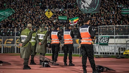 Las fuerzas de seguridad marroquíes vigilan la grada mientras los seguidores del Raja Club Athletic cantan consignas y agitan sus banderas.